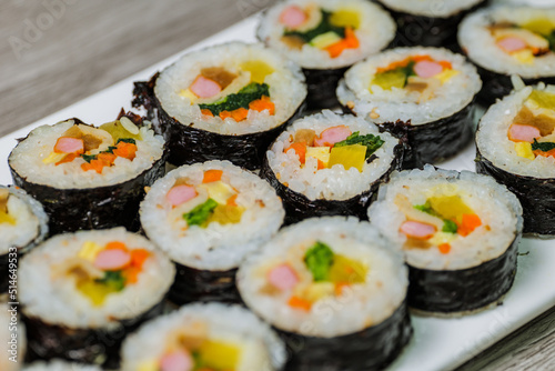 Korean food Gimbap : Rice seasoned with salt and sesame oil and rolled up in a sheet of roasted gim (dried laver) with spinach, carrots, and pickled white radish. The long roll is sliced and served in