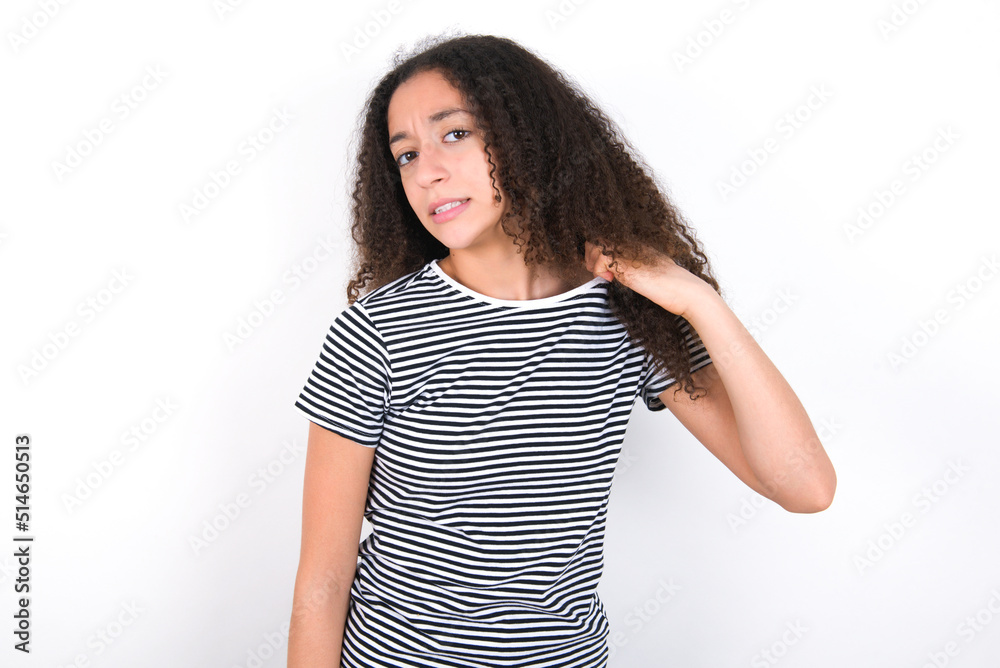 young beautiful girl with afro hairstyle wearing striped t-shirt over white wall stressed, anxious, tired and frustrated, pulling shirt neck, looking frustrated with problem young beautiful girl with afro hairstyle wearing striped t-shirt over white wall stressed, anxious, tired and frustrated, pulling shirt neck, looking frustrated with problem