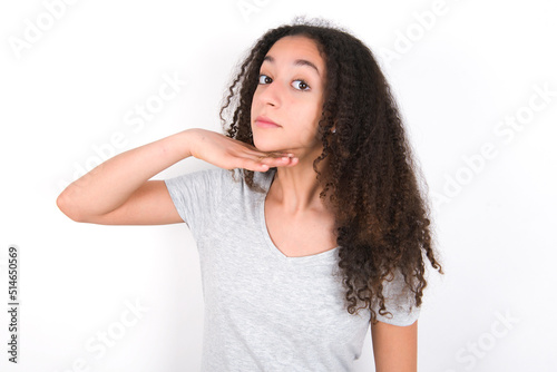 young beautiful girl with afro hairstyle wearing grey t-shirt over white wall cutting throat with hand as knife, threaten aggression with furious violence.