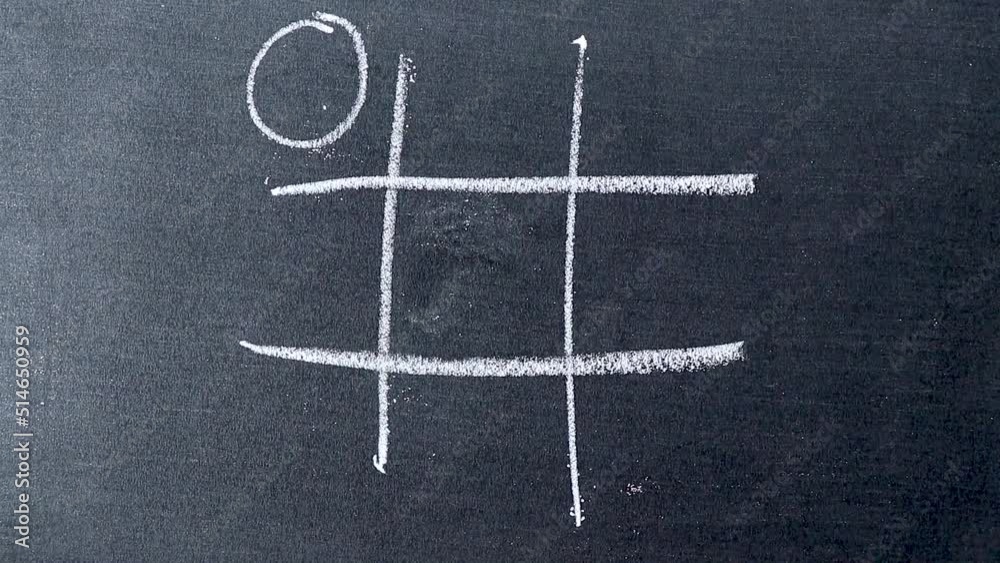 Hand hold white chalk drawing tic tac toe game on blackboard background and O is the win side