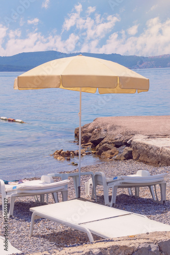 Summer beach vacation. Sun umbrella on coast of bay. Montenegro, Adriatic Sea, Bay of Kotor near Tivat city