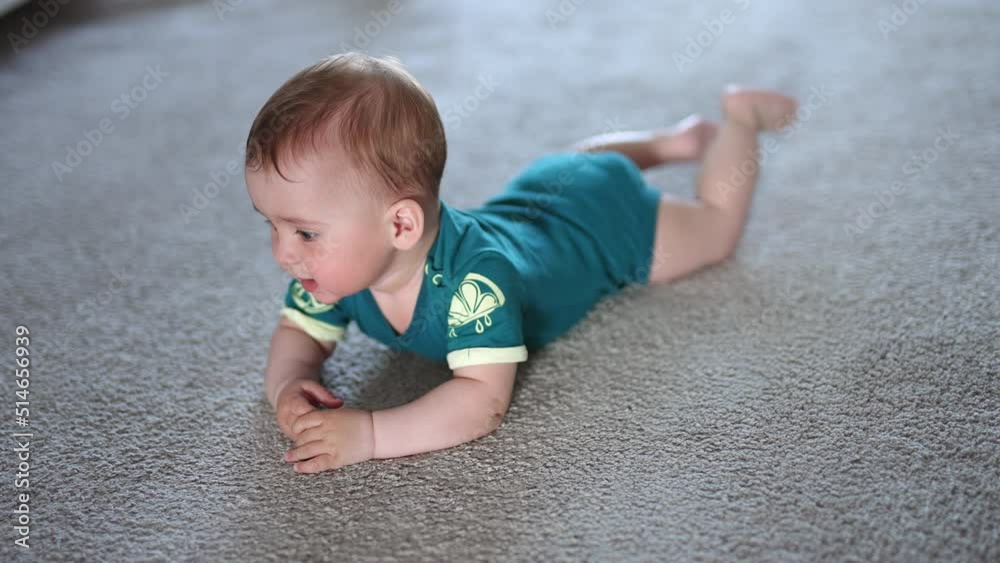 Nice baby boy lies on the floor looking up to the camera with surprise. Funny little child banging arms and legs by the floor. Nice baby boy lies on the floor looking up to the camera with surprise. Funny little child banging arms and legs by the floor.