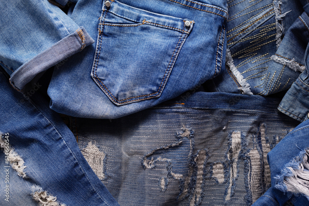 Heap of torn jeans denim background texture. Blue jeans fabric material surface