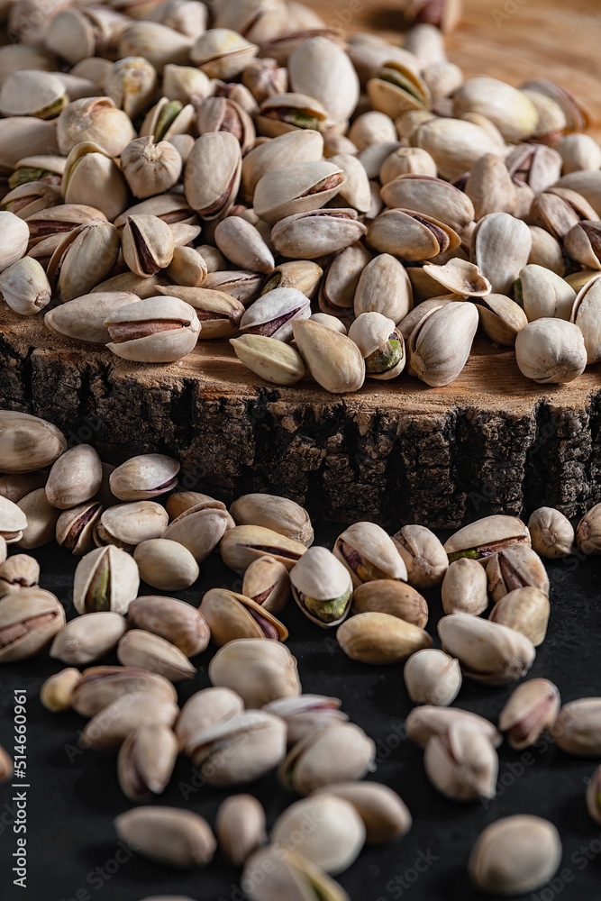 fried salty pistachio snacks are laid out on a wooden substrate on a dark background close-up fried salty pistachio snacks are laid out on a wooden substrate on a dark background close-up