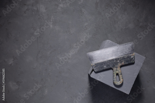 Concrete cube and construction work tools on floor background texture. Cement block and putty knife photo