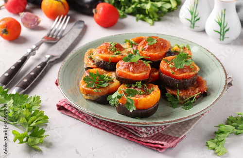 Eggplants and tomatoes baked with cheese and garlic served on plate on gray background
