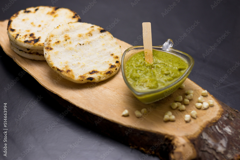 corn arepa traditional Colombian food on top of a log accompanied by sauce corn arepa traditional Colombian food on top of a log accompanied by sauce