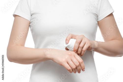 Cropped shot of a woman in white t-shirt holding a bottle of face cream with pump, isolated on white. Well-groomed short natural nails. © Snizhana