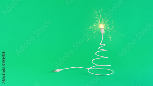 Creative digital technology Christmas arrangement made of USB cable in the shape of a Christmas tree and sparkles on a green background. Minimal New Year concept with copy space. Online holiday insp