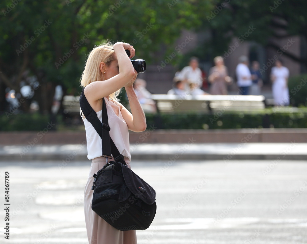 A blonde woman photographer on the street at work, St. Isaac's Square, St. Petersburg, Russia, July 2022