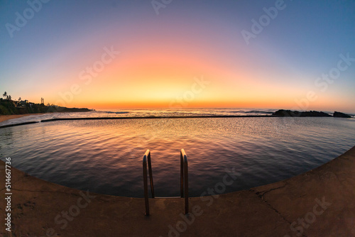 Canvastavla Beach dawn sunlight sky colors reflections over rocky tidal swimming pool with ocean sunrise nearby
