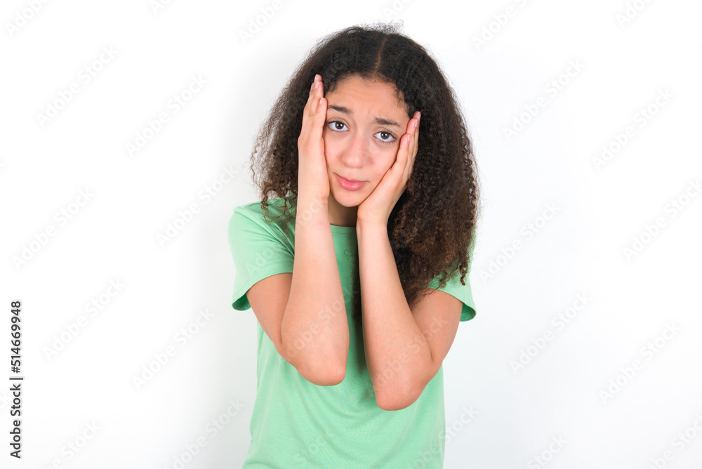 Teenager girl with afro hairstyle wearing green T-shirt over white wall Tired hands covering face, depression and sadness, upset and irritated for problem Teenager girl with afro hairstyle wearing green T-shirt over white wall Tired hands covering face, depression and sadness, upset and irritated for problem