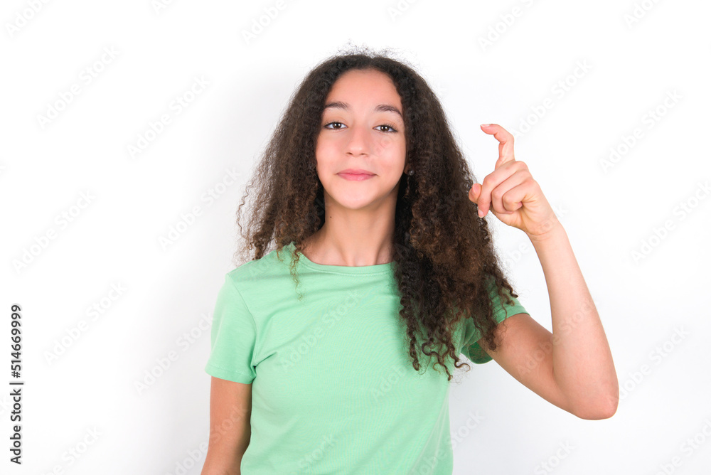 Teenager girl with afro hairstyle wearing green T-shirt over white wall pointing up with fingers number nine in Chinese sign language Jiu Teenager girl with afro hairstyle wearing green T-shirt over white wall pointing up with fingers number nine in Chinese sign language Jiu