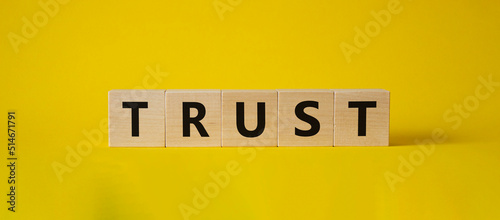 Trust symbol. Concept word Trust on wooden cubes. Beautiful yellow background. Business and Trust concept. Copy space.