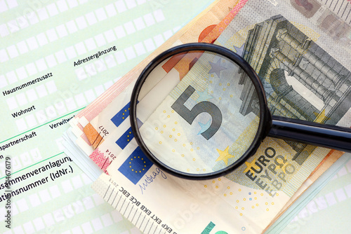 German income tax return form with magnifying glass and european euro money bills lies on accountant table close up. Taxpayers in Germany using euro currency to pay taxes photo