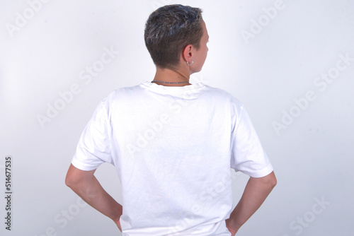 The back view of young woman with short hair wearing white t-shirt over white background Studio Shoot.