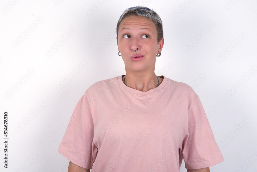 Shocked young woman with short hair wearing pink t-shirt over white background look empty space with open mouth screaming: Oh My God! I can't believe this. Shocked young woman with short hair wearing pink t-shirt over white background look empty space with open mouth screaming: Oh My God! I can't believe this.