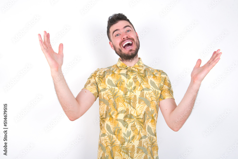 Cheerful Young caucasian man wearing Hawaiian t-shirt over white background making a welcome gesture raising arms over head. Cheerful Young caucasian man wearing Hawaiian t-shirt over white background making a welcome gesture raising arms over head.