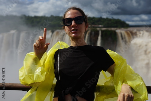 In the photo, a beautiful girl in a white shirt stands against the backdrop of the Iguazu Waterfalls, which are located on the border between Brazil and Argentina.
