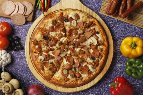 Flatbread pizza garnished with fresh angular on wooden pizza board top view dark stone background