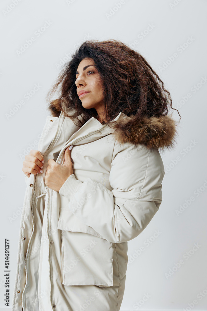 Serious Curly Pretty Latin Lady Wearing In Soft Warm Beige Winter Coat With Fur Hood Posing Isolated Looking Aside At White Studio Background. Fashion Huge Sale New Collection Concept Vertical Shot Serious Curly Pretty Latin Lady Wearing In Soft Warm Beige Winter Coat With Fur Hood Posing Isolated Looking Aside At White Studio Background. Fashion Huge Sale New Collection Concept Vertical Shot