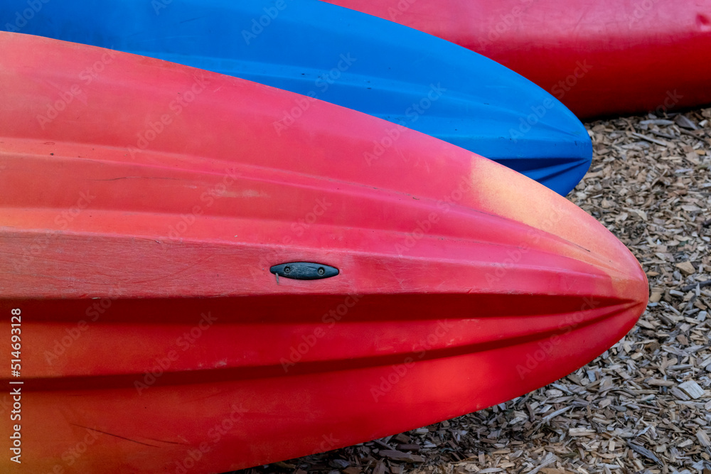 Red and blue kayaks on shore awaiting rental Red and blue kayaks on shore awaiting rental