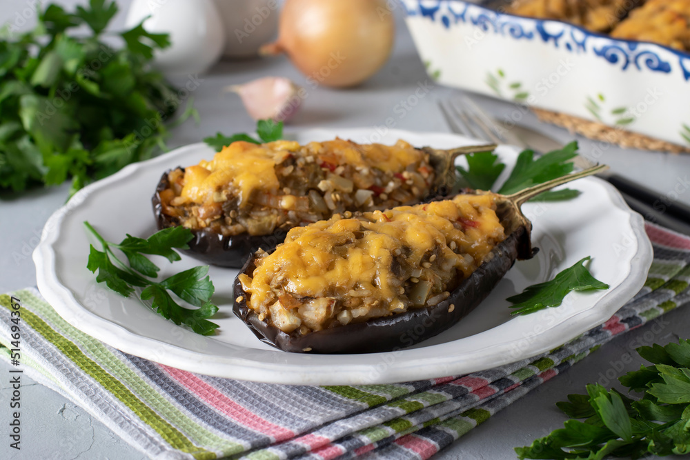Stuffed eggplant baked with cheese and garlic on a white plate on gray background Stuffed eggplant baked with cheese and garlic on a white plate on gray background