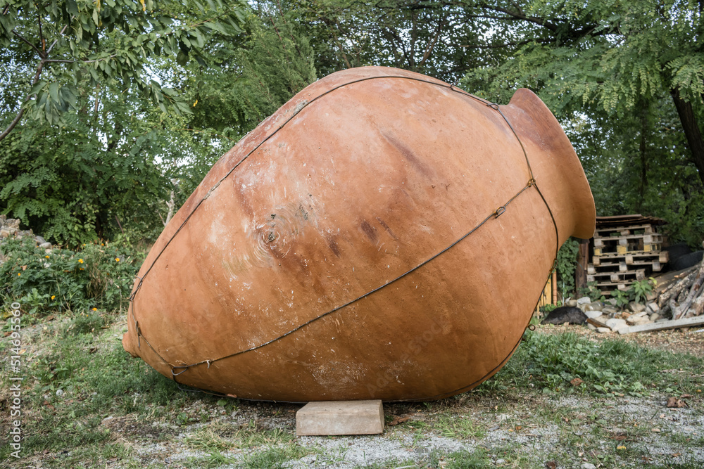 Big kvevri in garden in front of a stone wall, Georgia