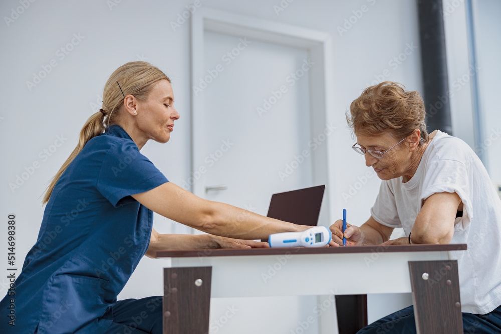 Fototapeta premium Female patient signing treatment agreement in doctor's office in clinic. High quality photo