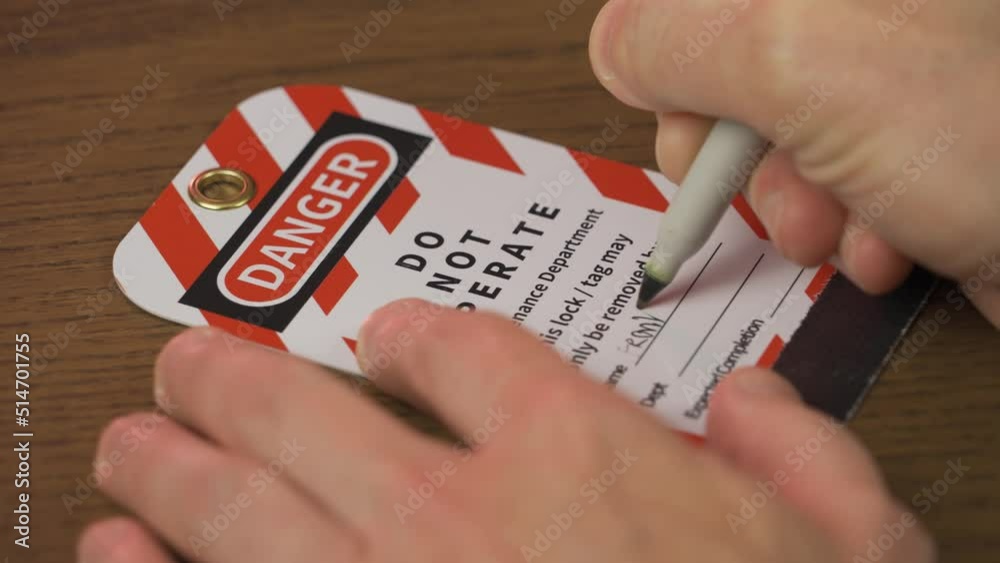 A close up view of a repair worker filling in a lockout/tagout tag before servicing a piece of machinery.
