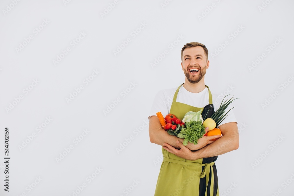 Happy man holding many different fresh vegetables on white background Happy man holding many different fresh vegetables on white background