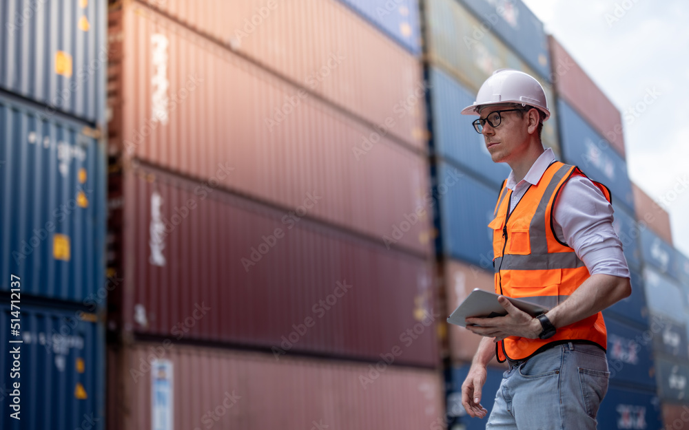 Container operator holding a tablet to do his routine inspection while working in container yards. Container operator holding a tablet to do his routine inspection while working in container yards.