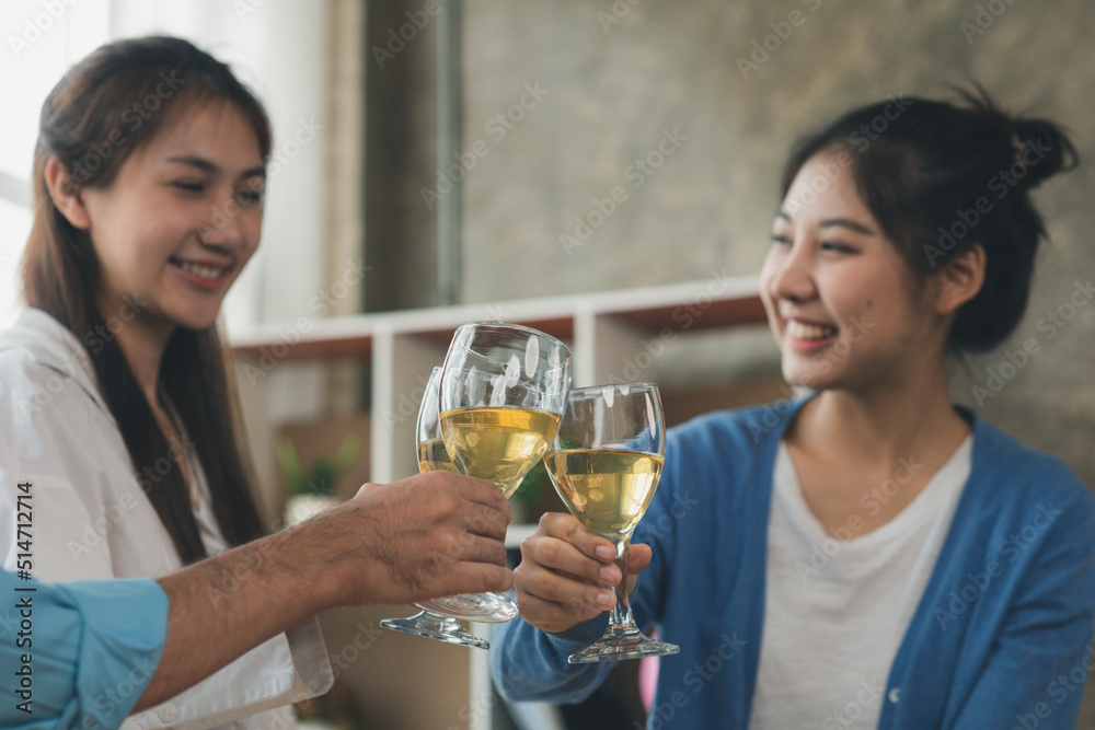 Group of young Asians clinking white wine glasses, startup company parties, New Year's parties, annual company parties, alcoholic beverages. Company employee party catering ideas, celebrations.