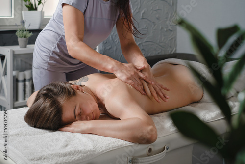 Caucasian woman having body treatment in professional clinic. Oil shoulder massage, Asian spa and healthcare concept. Relaxation and pain relief from physiotherapist 