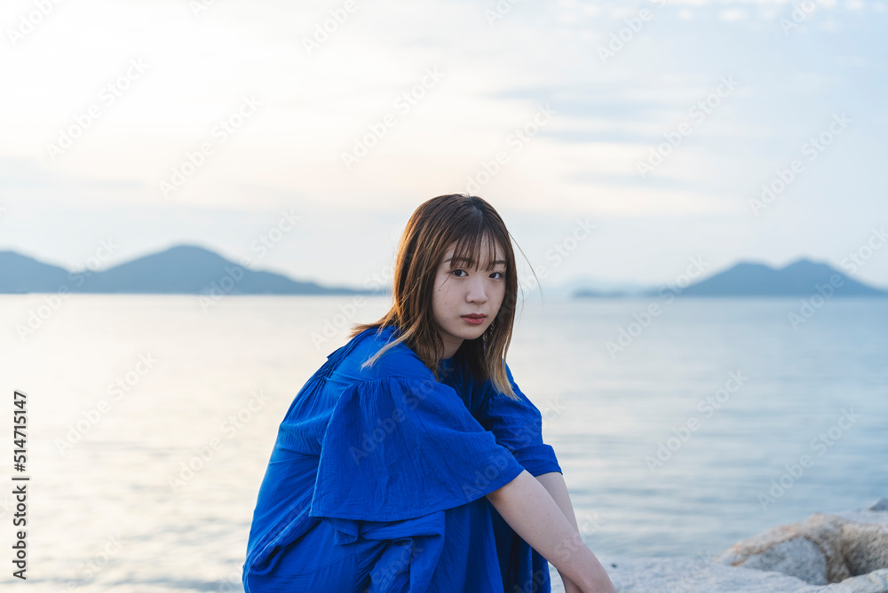 夕暮れの海にいる青いワンピースの女性 夕暮れの海にいる青いワンピースの女性