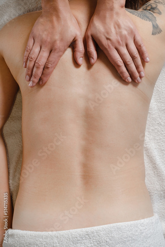 Caucasian woman having massage treatment in therapy clinic. Oil back massage  Spa and healthcare concept. Pain relief. Close-up  top view with copy space. Hands on human back  spine