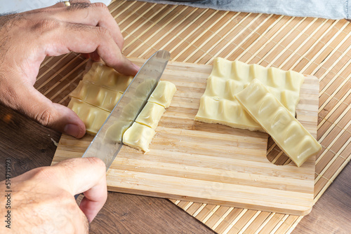 man cutting pieces of white chocolate on wooden cutting board