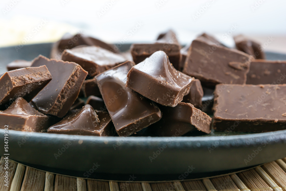 close up shot of milk chocolate pieces on a dark plate close up shot of milk chocolate pieces on a dark plate