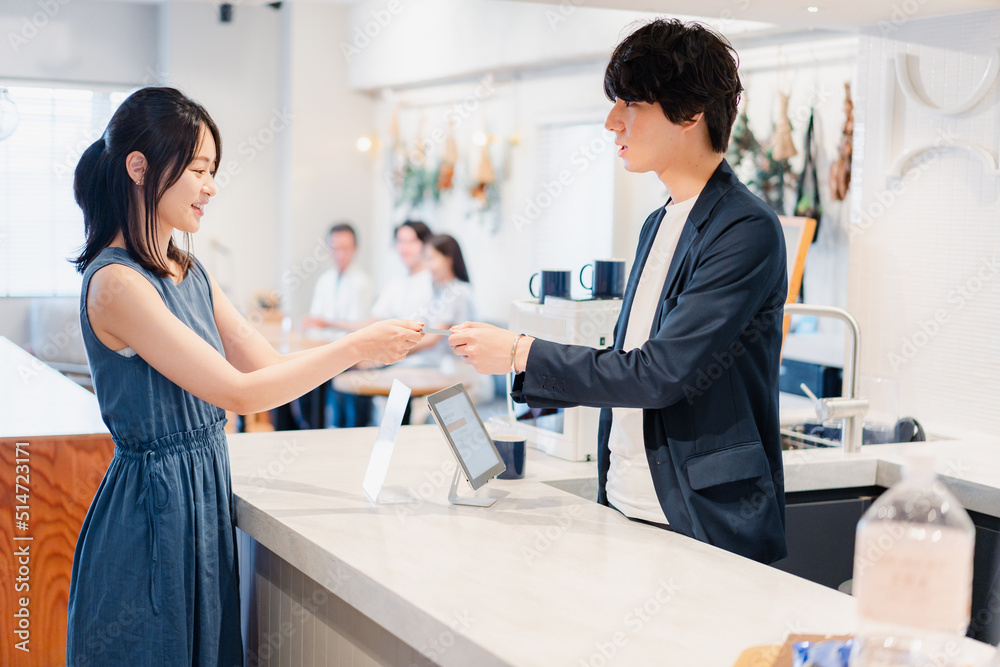 Fototapeta premium レジでクレジットカード決済をする若い女性