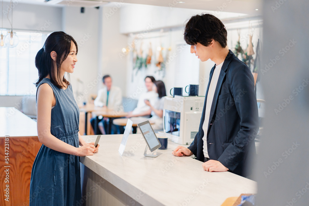 Fototapeta premium レジでクレジットカード決済をする若い女性