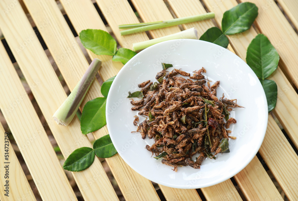 spicy fried cricket with herbal leaf on wooden table for eating spicy fried cricket with herbal leaf on wooden table for eating