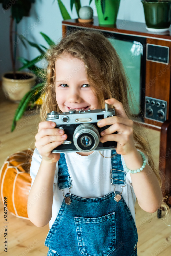 the white teen girl takes pictures on a retro camera and laughs. hobby for kids and happy childhood the white teen girl takes pictures on a retro camera and laughs. hobby for kids and happy childhood