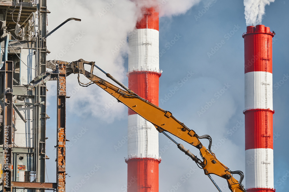Hydraulic cutter destroys old building against chimneys Hydraulic cutter destroys old building against chimneys