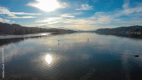 Sunset view on Woerthersee in Poertschach in Carinthia, Austria.Few ducks crossing the lake. Calm surface of the lake is reflecting the mountains,sunbeams.Sunny day. Relaxed feeling. Alps, Lake Woerth