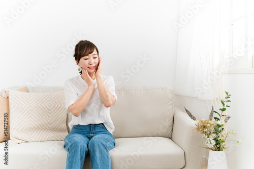 ソファで肌を触って紫外線対策する日本人女性（美容・スキンケア） 