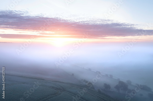 Majestic drone landscape image of sea of fog rolling across South Downs English countryside during Spring sunrise