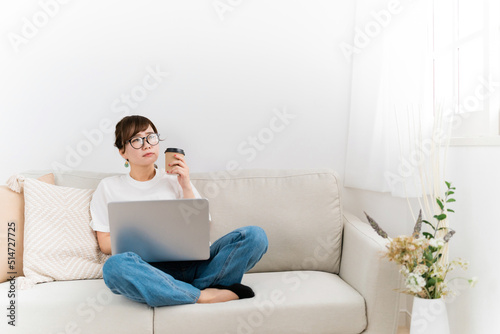 家のソファでパソコンを使う日本人女性（困る・悩む） 