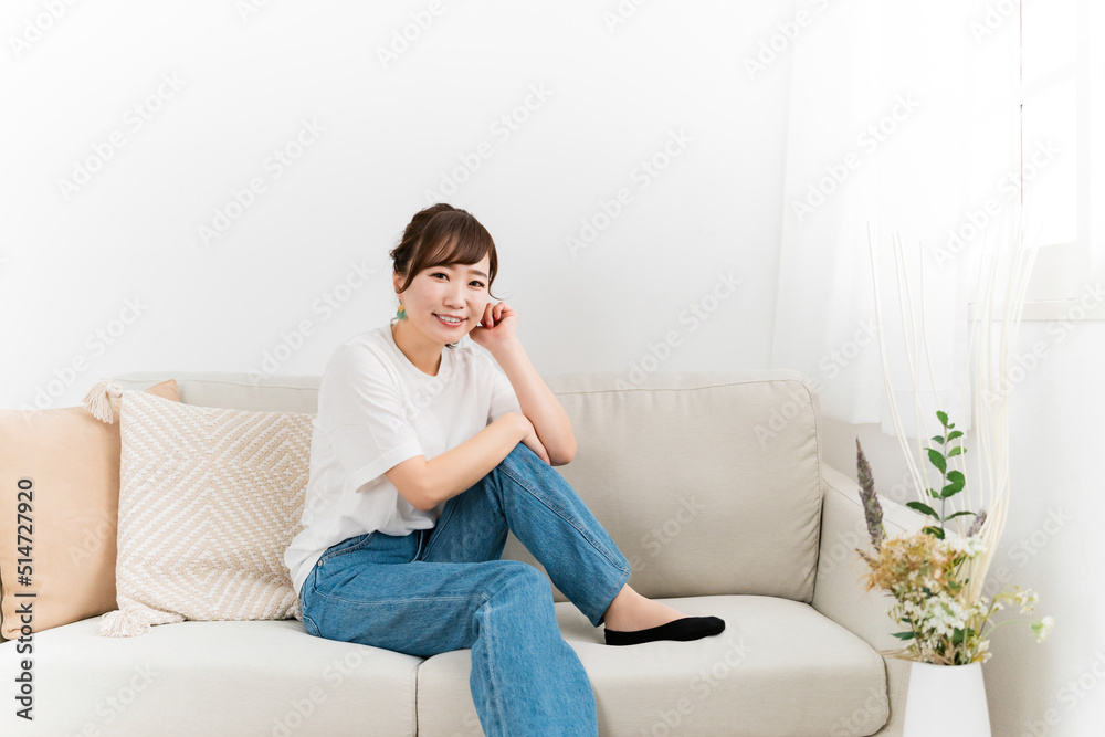 家のソファでリラックスするデニム姿の日本人女性（カメラ目線）
