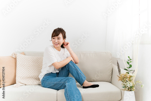 家のソファでリラックスするデニム姿の日本人女性 
