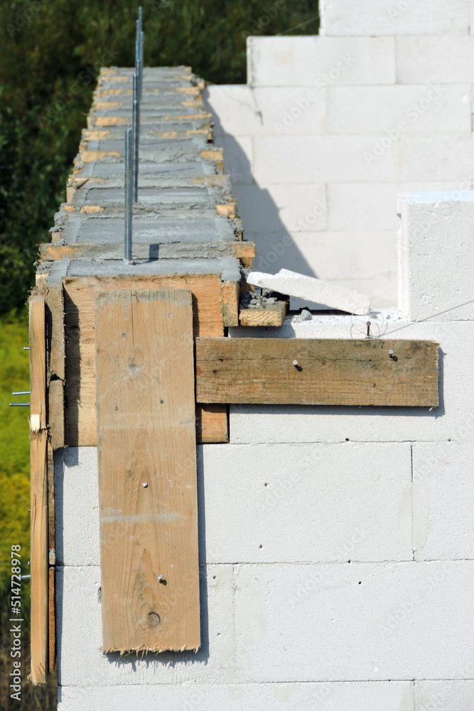 A reinforced concrete beam and a wooden formwork on the first floor of a house under construction, walls made of autoclaved aerated concrete A reinforced concrete beam and a wooden formwork on the first floor of a house under construction, walls made of autoclaved aerated concrete